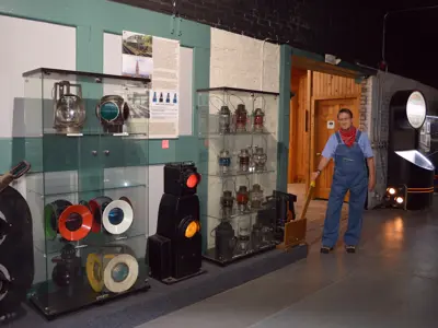 A photo of the Lantern and Signals display in the freight house exhibit space with a man dressed as an engineer, at the NNYCRRM