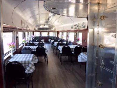 Observation car interior, showing tables each with checkered table clothes and decorative vases 