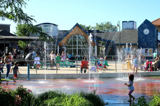 Kids playing in the splash pad at NIBCO Water & Ice Park with the Summer Chill stage and audience in the background