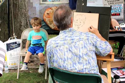 Young boy having a caricature drawn at the Rhapsody Arts & Music Festival