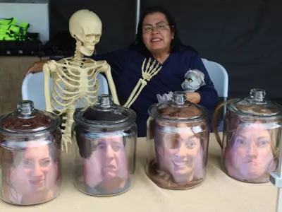 Heads in jars decoration and volunteer at Elkhart Environmental Center booth at Haunted Walk event